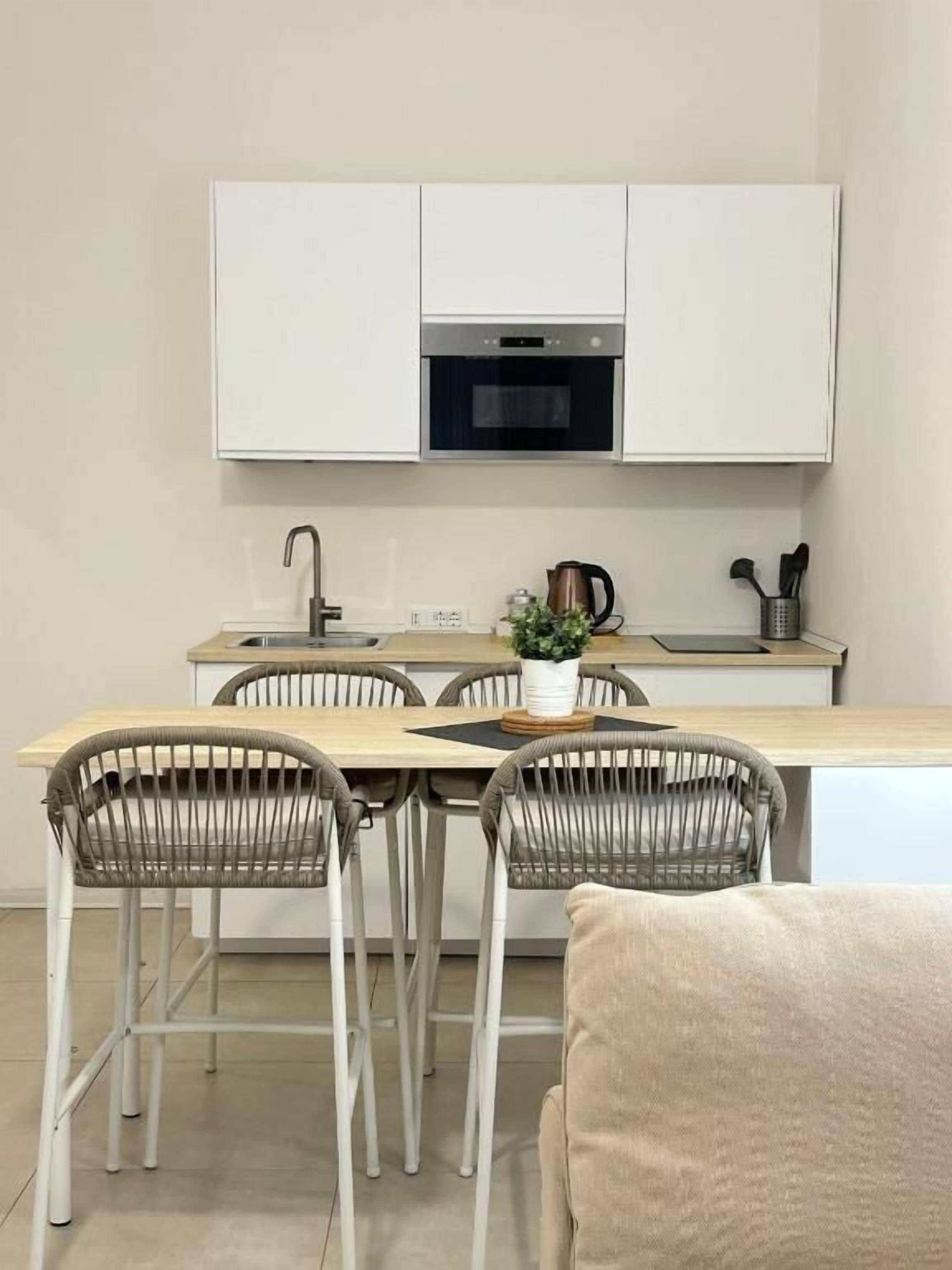 A modern kitchen with white cabinets, a microwave, and a dining area with wicker chairs.