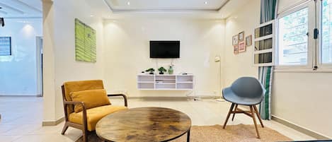 A modern living room with a sofa, a round coffee table, and a TV mounted on the wall.