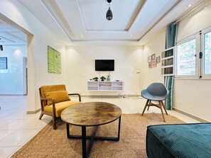 Una sala de estar moderna con un sofá, una mesa de centro redonda y un televisor montado en la pared.