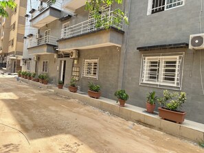 Un edificio residencial de varios pisos con balcones, plantas en macetas y unidades de aire acondicionado.