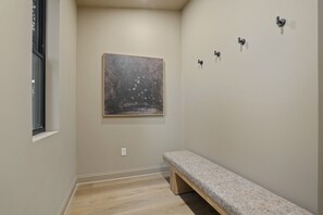 Un pasillo con un banco, un cuadro y luminarias fijadas a la pared.