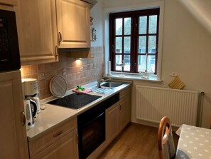 Eine Küche mit Einbauofen, Kaffeemaschine und einem Fenster mit Blick nach draußen.