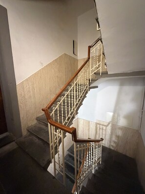 Eine Treppe mit hölzernen Geländern und Metallspindeln, die zu einer oberen Etage führt.