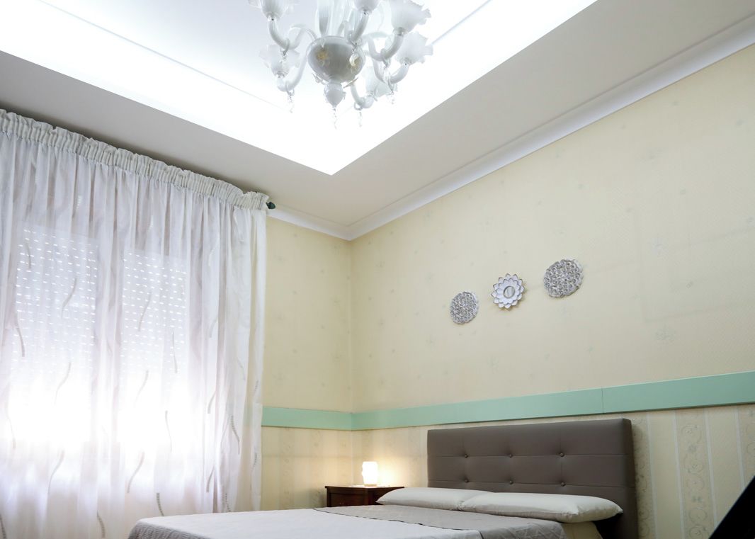 A bedroom with a bed, a nightstand, and a skylight.