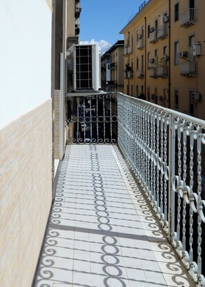 A tiled balcony with a metal railing, overlooking a street with buildings. - Maureen Holiday House (napoli)