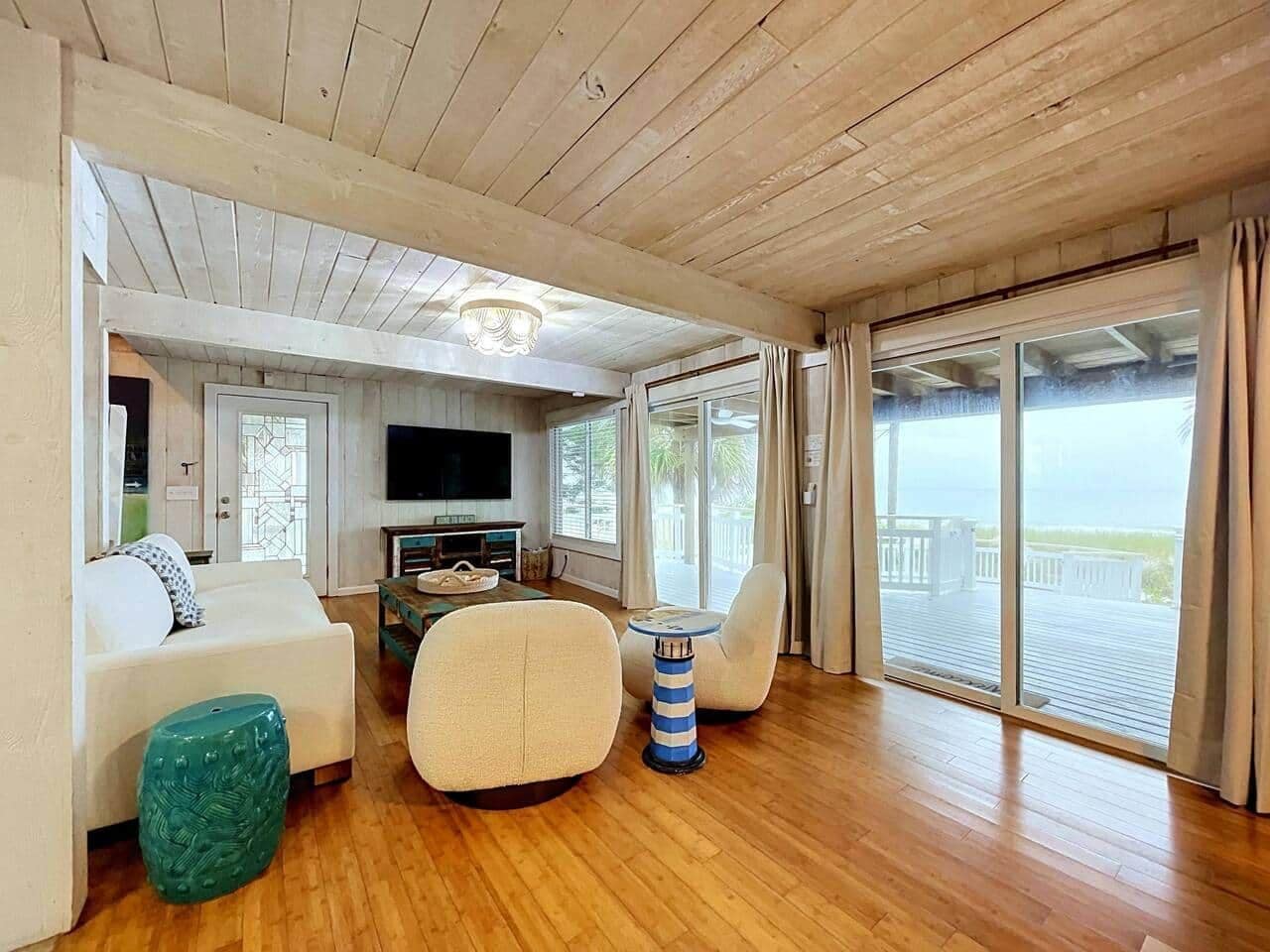 Un vaste espace de vie doté d’un plafond en bois, d’un téléviseur, d’un canapé, d’une table basse et offrant une vue sur l’extérieur grâce à de grandes portes coulissantes.
