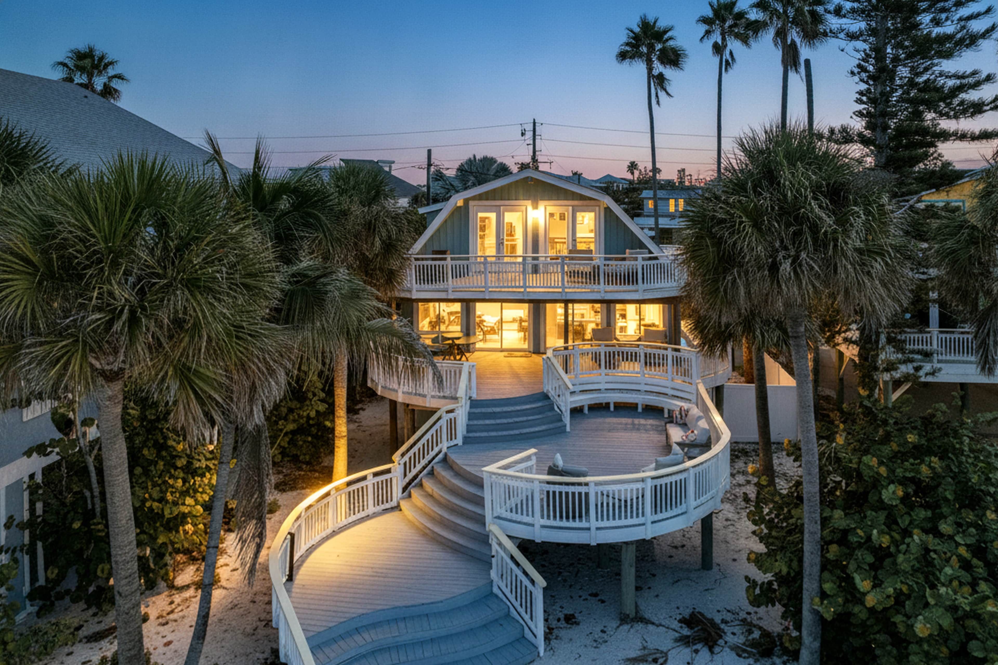 Une propriété située en bord de mer, comprenant un bâtiment à deux étages, une terrasse extérieure couverte et un escalier menant à l’étage supérieur.