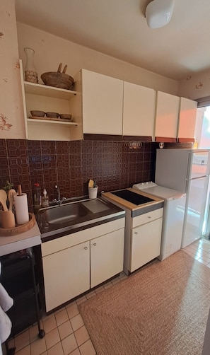 A kitchen with white cabinets, a black countertop, a sink, and a refrigerator. - Vrbo Property (Cannes)