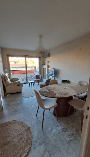 A living room with a round table, chairs, a sofa, a TV, and a balcony with a view. - Vrbo Property (Cannes)
