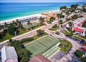 Een kustgebied met een tennisbaan, een strand en een weg met een rotonde.