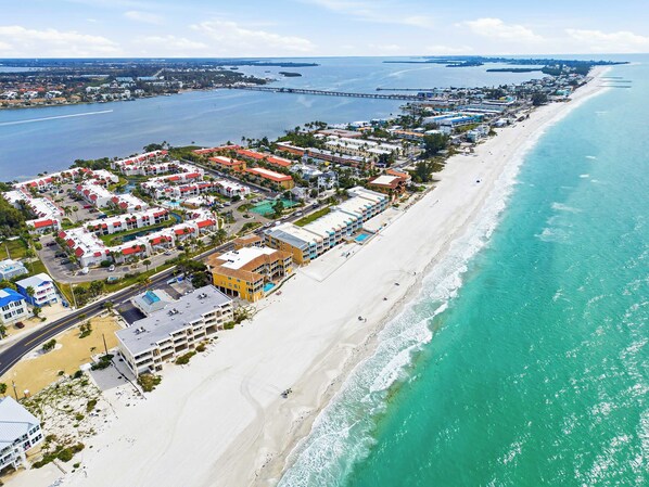 A coastal hotel with multiple buildings, a beach, and a pier in the background. - Dans Florida Condos Ocean Sands at Runaway Bay (Bradenton Beach)