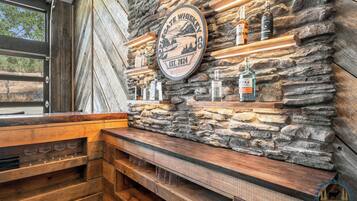 Un coin bar au style rustique, avec un mur en pierre, des étagères en bois et un banc.