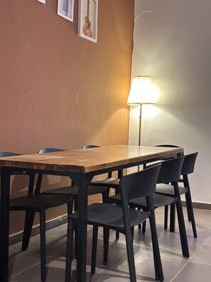 A dining area with a wooden table and black chairs, a lamp, and framed pictures on the wall. - Vrbo Property (Dakar)