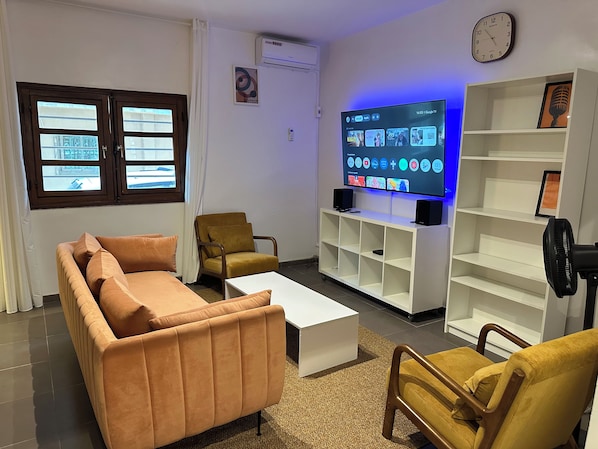 A living room with a sofa, armchairs, a coffee table, a TV, and a bookshelf. - Vrbo Property (Dakar)
