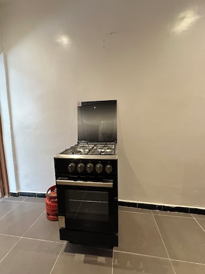 A kitchen with a gas stove, oven, and a red gas cylinder. - Vrbo Property (Dakar)