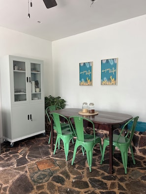 A dining area with a wooden table, green chairs, a cabinet, and two wall art pieces. - Cozy 1-bedroom apartment in tranquil Departamento de Santa Bárbara with AC (Departamento de Santa Bárbara)