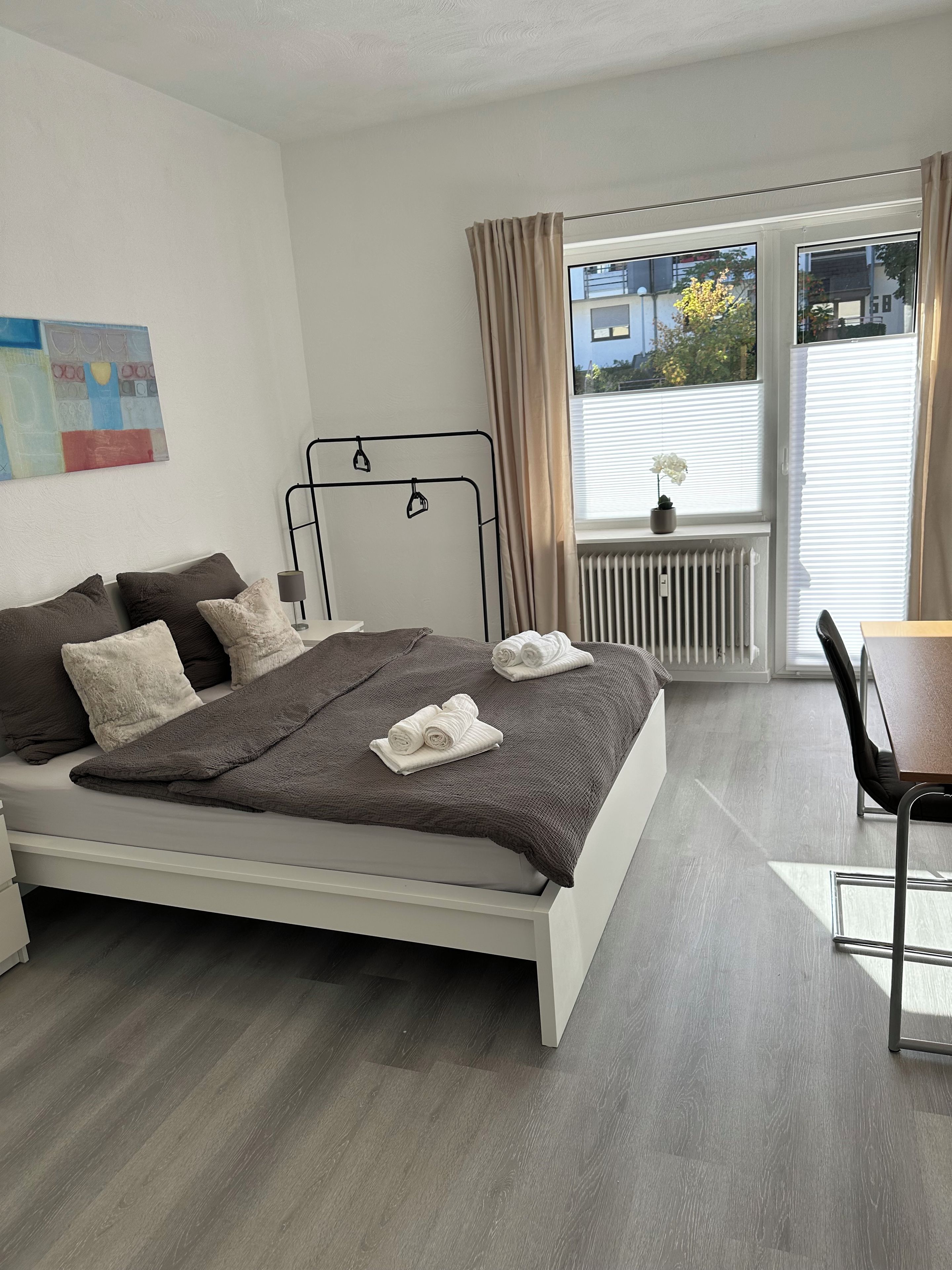 Un dormitorio moderno con cama, escritorio y ventana con vistas al exterior.