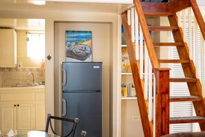 Eine Küche mit Kühlschrank, einem Bild an der Wand und einer Holztreppe.