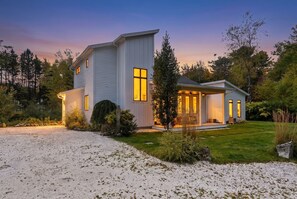 A two-story house with a covered porch and a gravel driveway. - Modern Coastal Cottage|Hot Tub|Privacy|BEST Locati (Kennebunk)