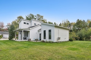 A two-story house with a covered porch and a lawn in front. - Modern Coastal Cottage|Hot Tub|Privacy|BEST Locati (Kennebunk)