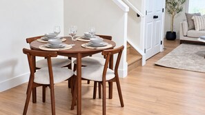 A dining area with a round wooden table, four chairs, and a set of plates and glasses. - 3 BR Home-7 minutes from West Edmonton Mall (Edmonton)