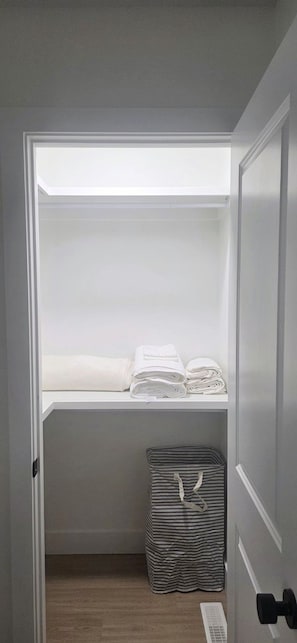Un vestidor con estantes para ropa doblada y un contenedor de almacenamiento.