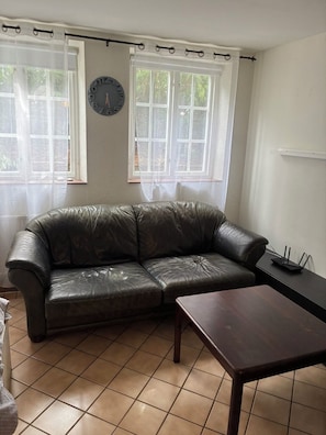 Una sala de estar con un sofá de cuero, una mesa de madera y un reloj en la pared.