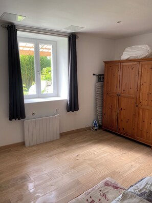 A room with a radiator, wooden wardrobe, and a window with curtains. - Vrbo Property (Bourg)