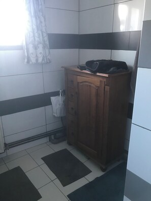 A bathroom with a wooden cabinet, a white towel, and a black mat on the floor. - Vrbo Property (Bourg)