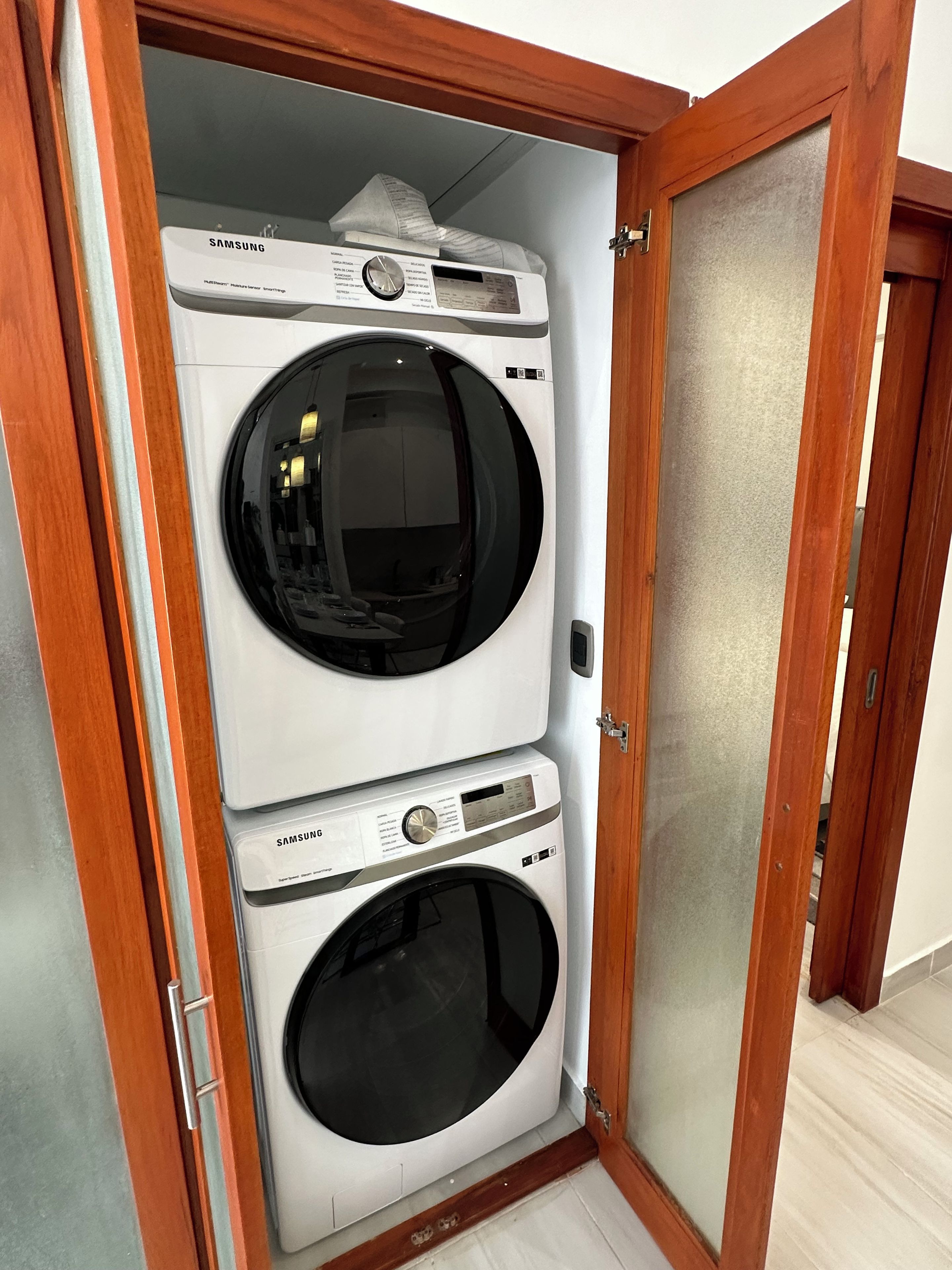 Un cuarto de lavandería con dos lavadoras apiladas, una encima de la otra, y una puerta de gabinete de madera.