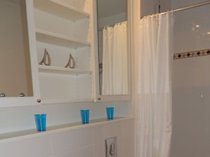 Un bagno con una parete rivestita in piastrelle bianche, uno specchio e una tenda da doccia.