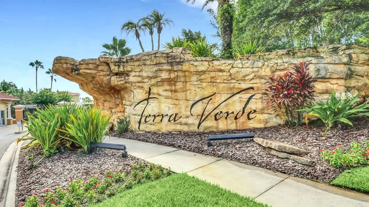 Un espace aménagé avec un mur de pierres sur lequel est inscrit le texte « Terra Verde » et qui est entouré de verdure.