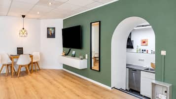 A modern living space with a dining area, kitchen, and a large mirror.
