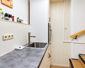 A kitchen with a stainless steel sink, a countertop, and a wooden staircase. - Modern Apartment in the Heart of Romhild, Thuringia (Roemhild)