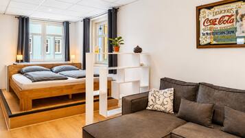 A modern bedroom with a wooden bed, a sofa, and a wall-mounted shelf.