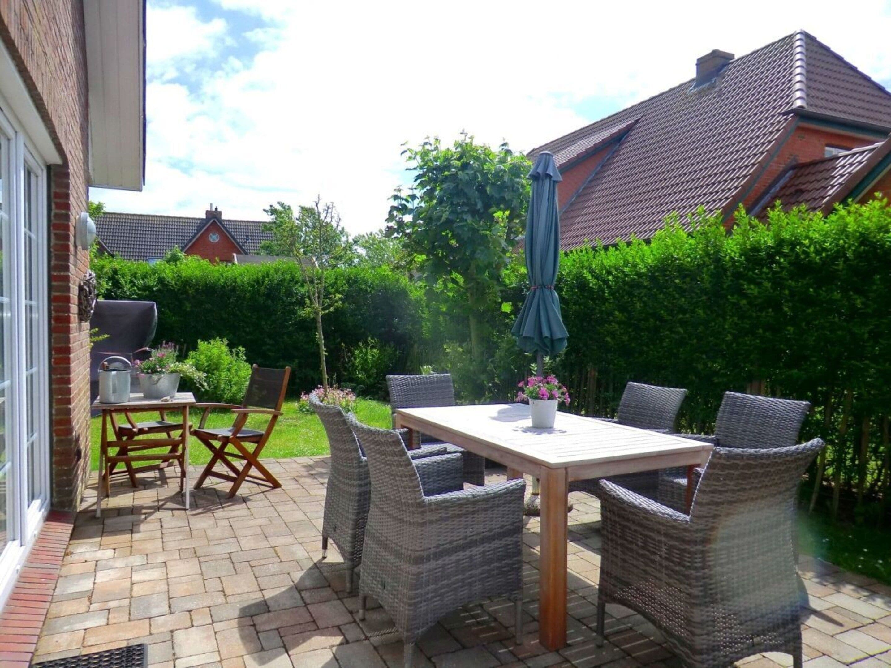 Un patio al aire libre con mobiliario de mimbre, una mesa y una parrilla.