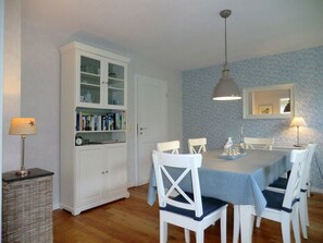 A dining area with a table, chairs, a cabinet with glass doors, a lamp, and a wall-mounted mirror. - Holiday Home in Oevenum With Swimming Pool (Oevenum)