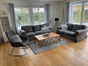 A modern living room with two grey sofas, a wooden coffee table, and a black chair. - Holiday Home in Oevenum With Swimming Pool (Oevenum)