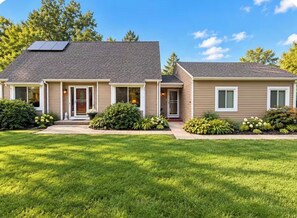 A two-story house with a sloped roof, a front porch, and a solar panel. - Charming pet friendly 3-bedroom house with deck and fenced yard Bloomfield (Bloomfield)