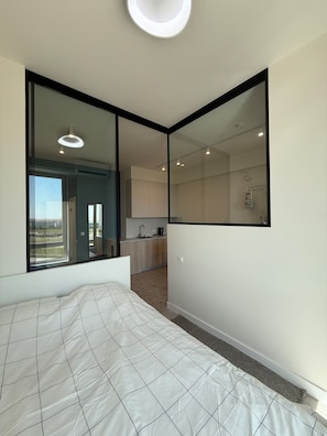 A bedroom with a large bed, a window, and a view of the outside. - Cozy clean & minimalistic apartment near Airport, with balcony & view! (Chișinău)
