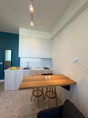 A modern kitchen with white cabinets, a wooden dining table, and a bar area. - Cozy clean & minimalistic apartment near Airport, with balcony & view! (Chișinău)