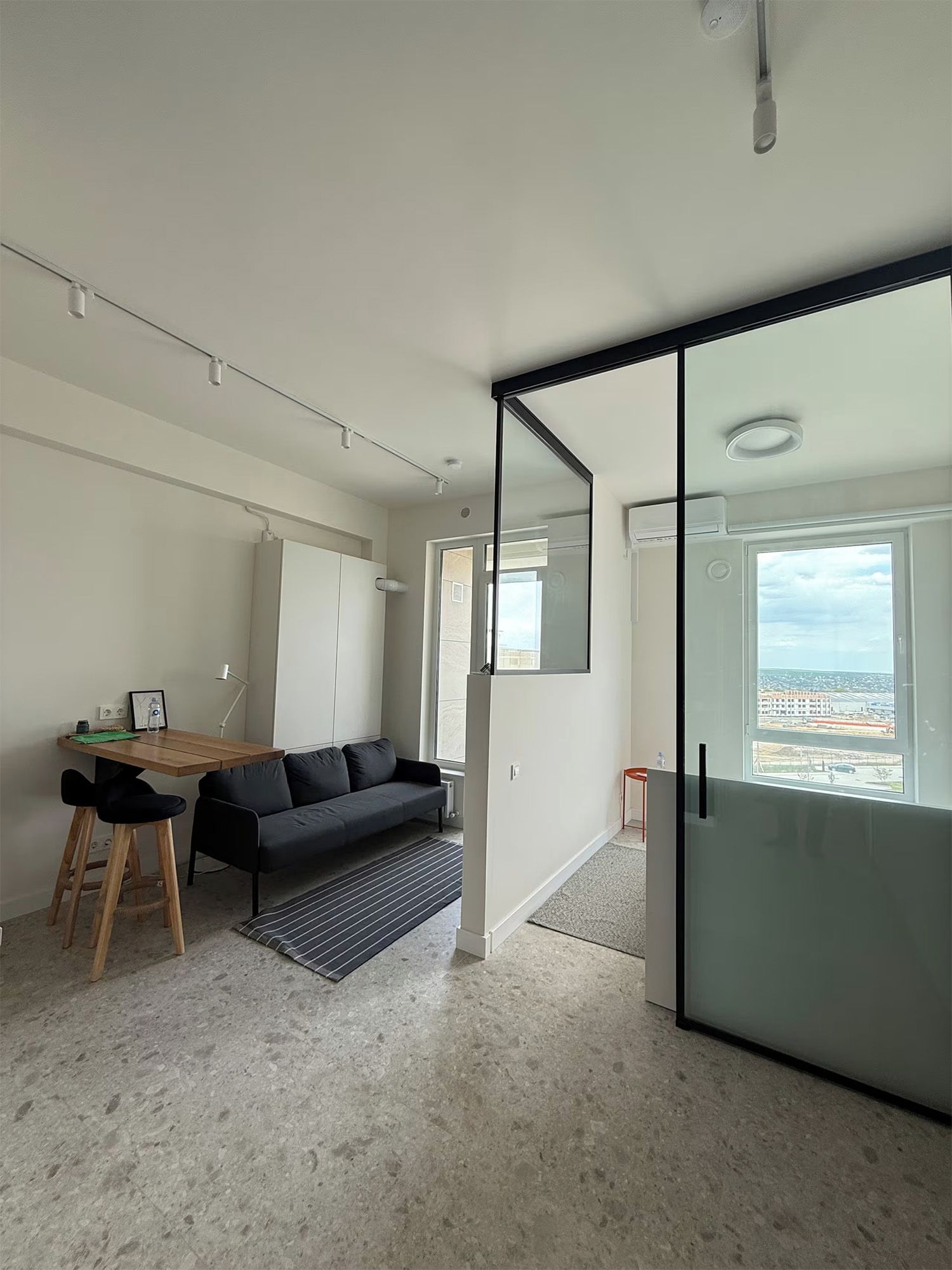 Een modern interieur met een bank, een eettafel en een groot raam met uitzicht op de stad.