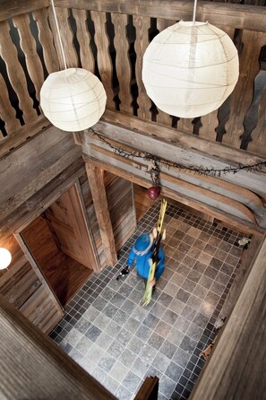Un intérieur en bois avec un plafond haut, un sol carrelé et deux lanternes en papier suspendues.