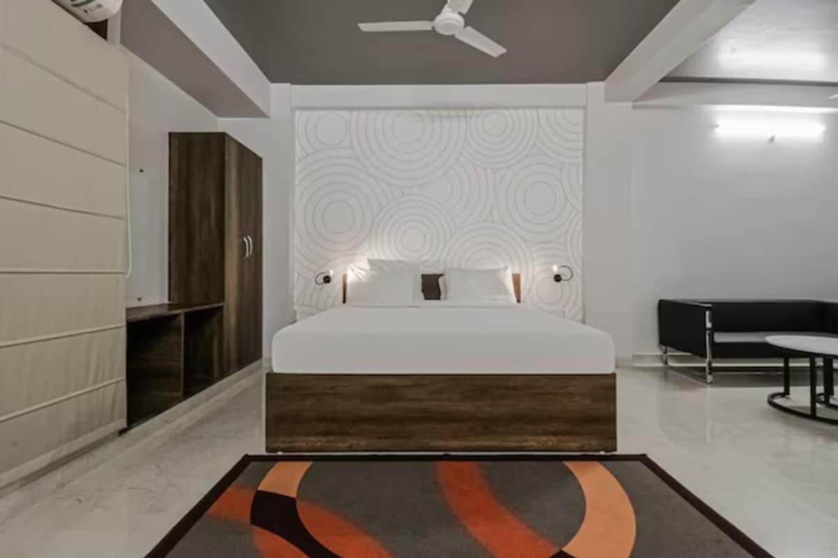 Un dormitorio con cama, ventilador de techo, pared con diseño y escritorio con silla.
