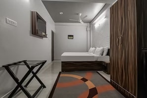 Un dormitorio con cama, armario, ventilador de techo y una pequeña mesa.