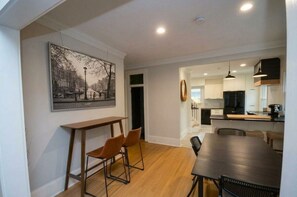 A modern kitchen with white cabinets, a black refrigerator, and pendant lighting. - Modern Huntersville Retreat : Minutes to Lake Norman & Birkdale Village! (Huntersville)