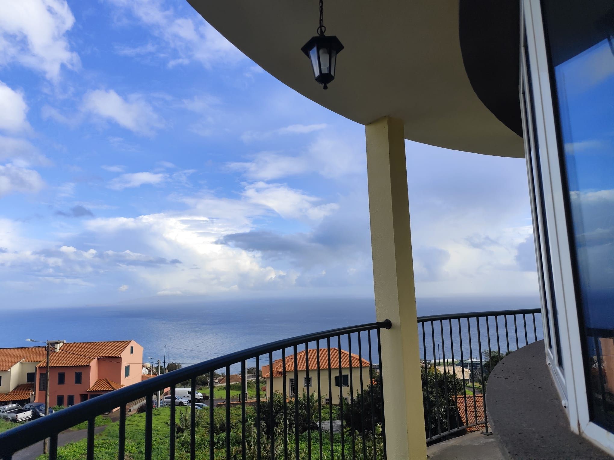 A balcony with a view of the sea and buildings.