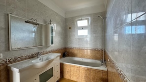 Une salle de bain équipée d’un lavabo, d’un meuble-lavabo, d’une baignoire et d’une douche.