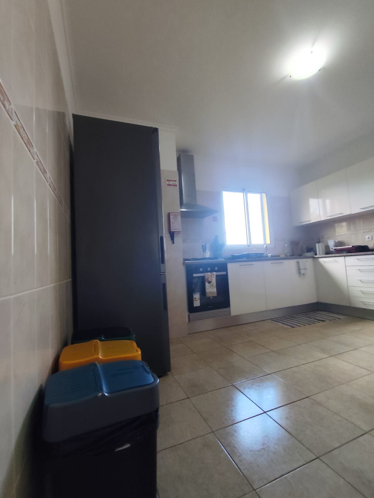 Una cocina con refrigerador, horno y ventana.