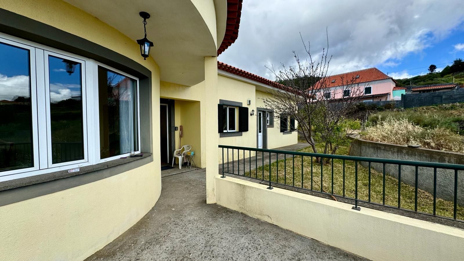 Un bâtiment à la façade incurvée, doté de grandes fenêtres et d’un petit espace extérieur aménagé en coin salon.